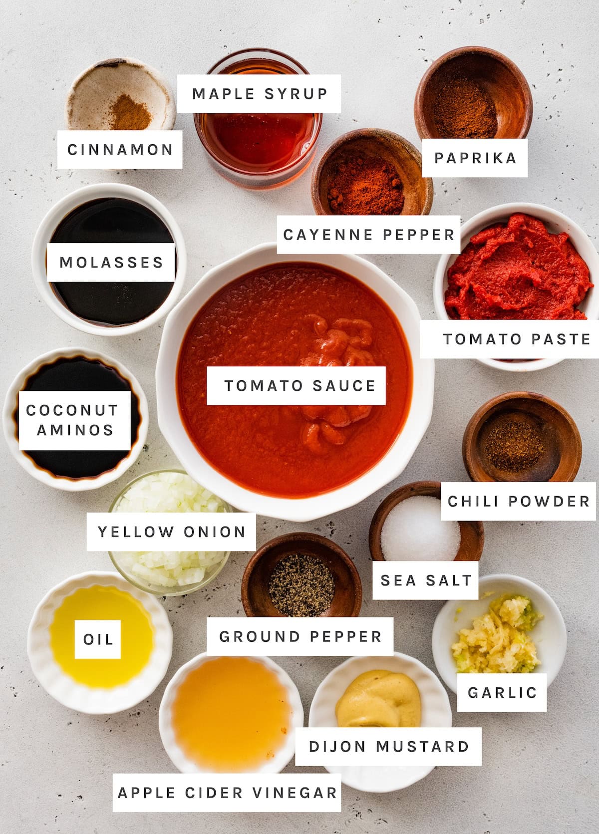 Healthy Homemade BBQ Sauce ingredients: Cinnamon, Maple Syrup, Paprika, Cayenne Pepper, Tomato Paste, Tomato Sauce, Chili Powder, Sea Salt, Garlic, Dijon Mustard, Apple Cider Vinegar, Ground Pepper, Oil, Yellow Onion, Coconut Aminos, Molasses.