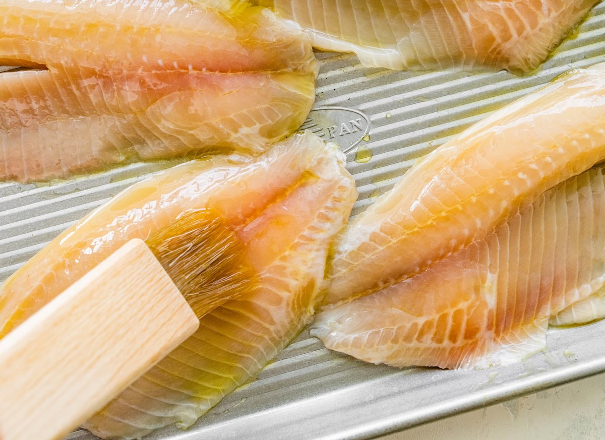 The tilapia filets being brushed with oil.