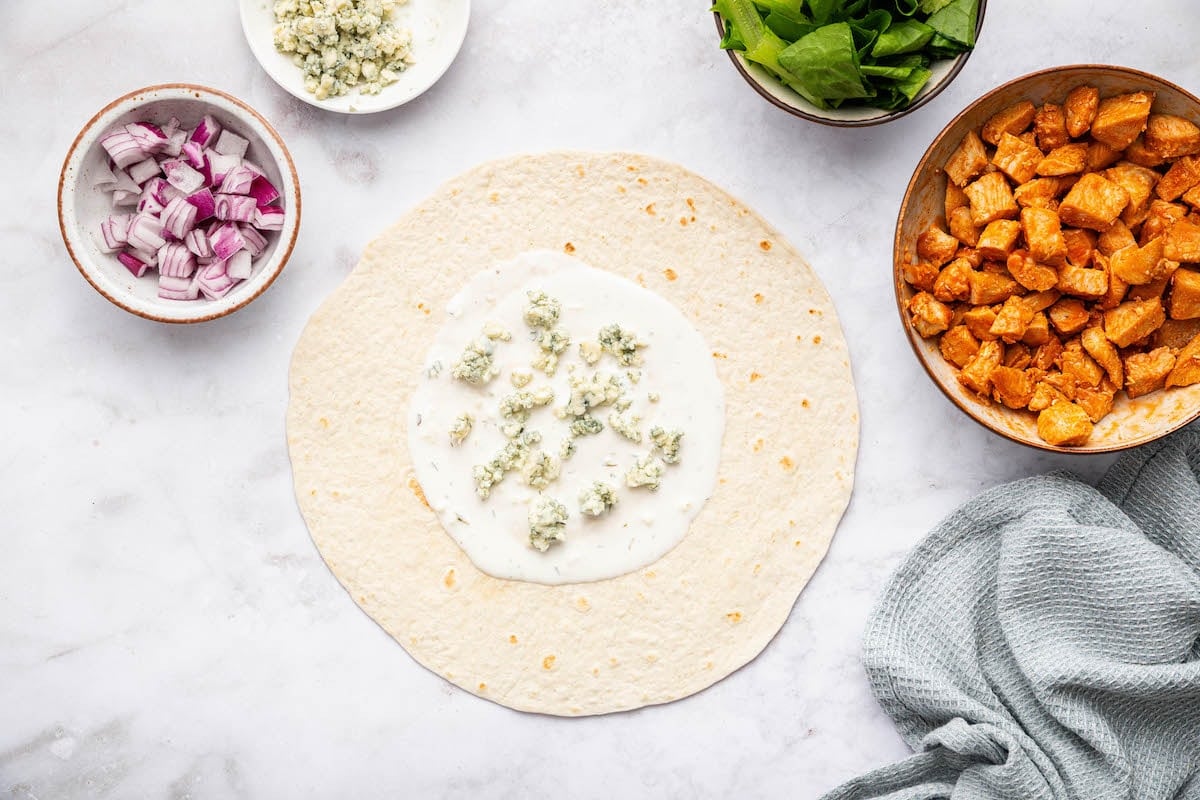 Flour tortilla spread with ranch dressing and sprinkled with crumbled blue cheese.
