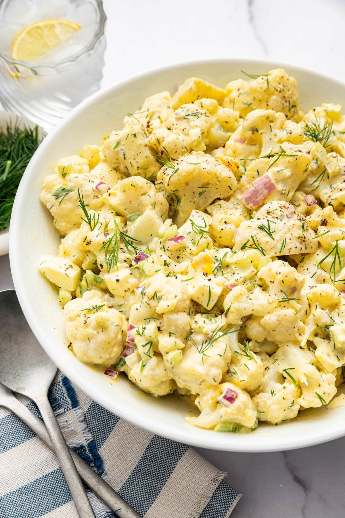 Cauliflower potato salad in a large serving bowl topped with fresh dill.
