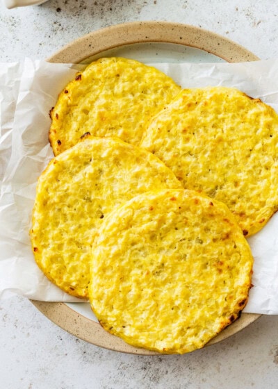 Four cauliflower thins on a plate line with parchment paper.