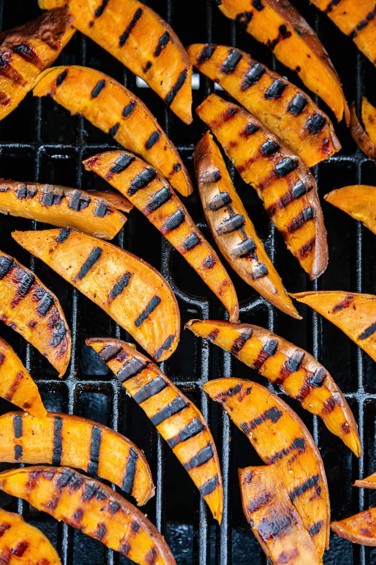 Grilled sweet potatoes cooking on a grill.