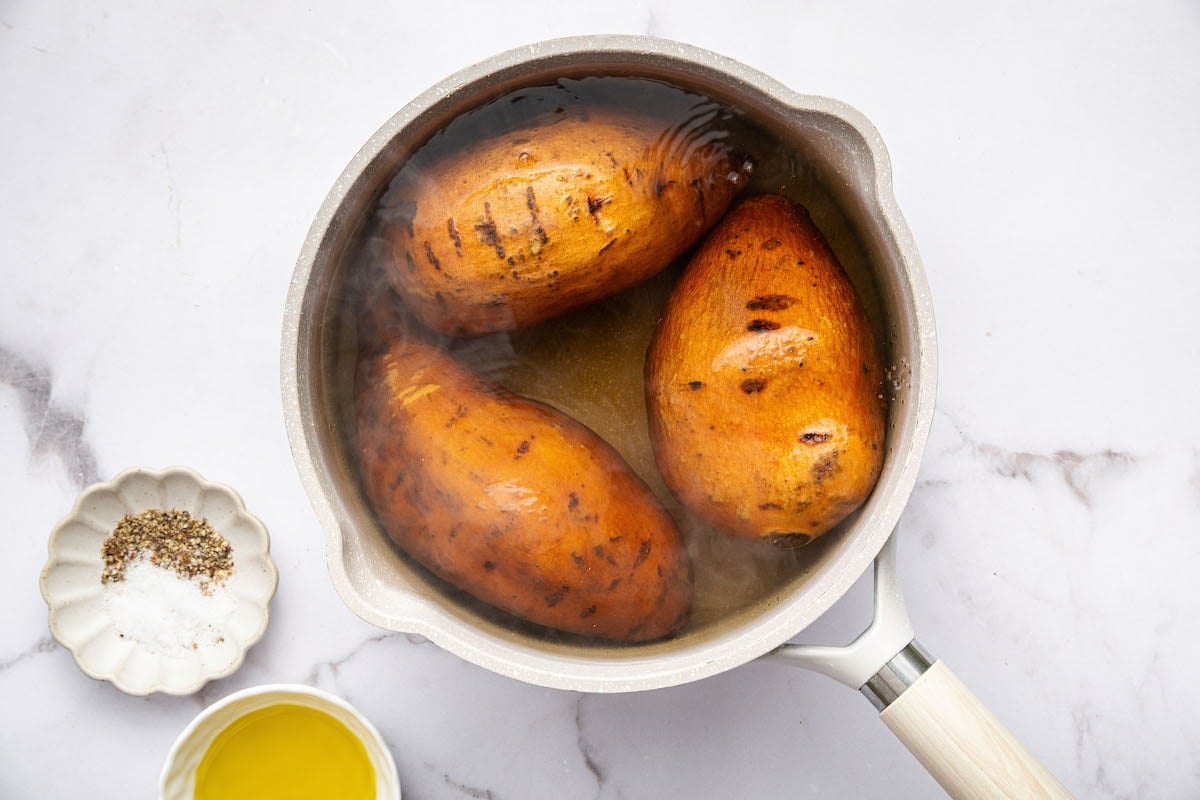 Three sweet potatoes boiling in water.