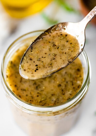 Spoonful of homemade Italian dressing showing herbs and texture.