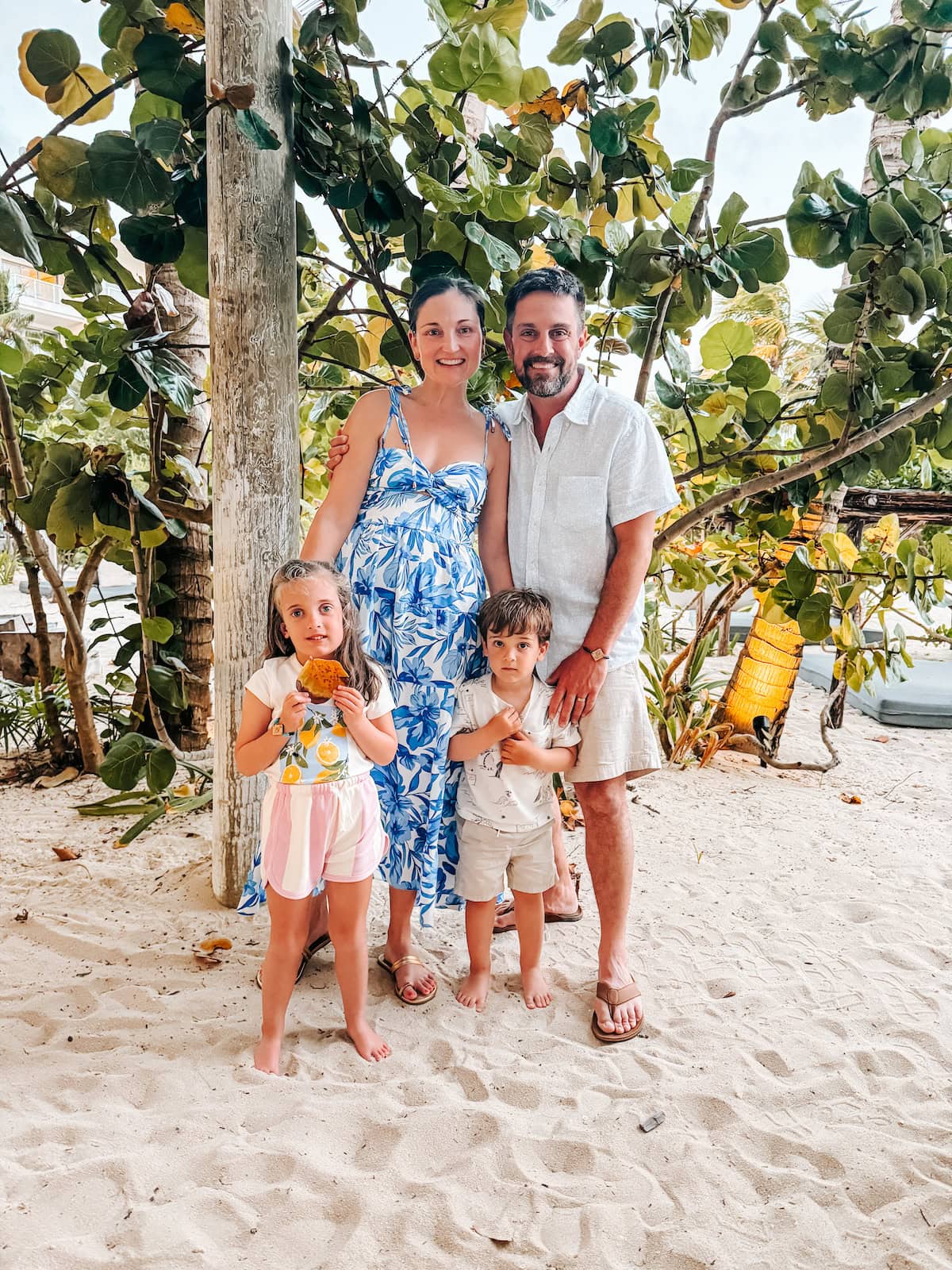 A family poses for a photo on a white sandy beach.