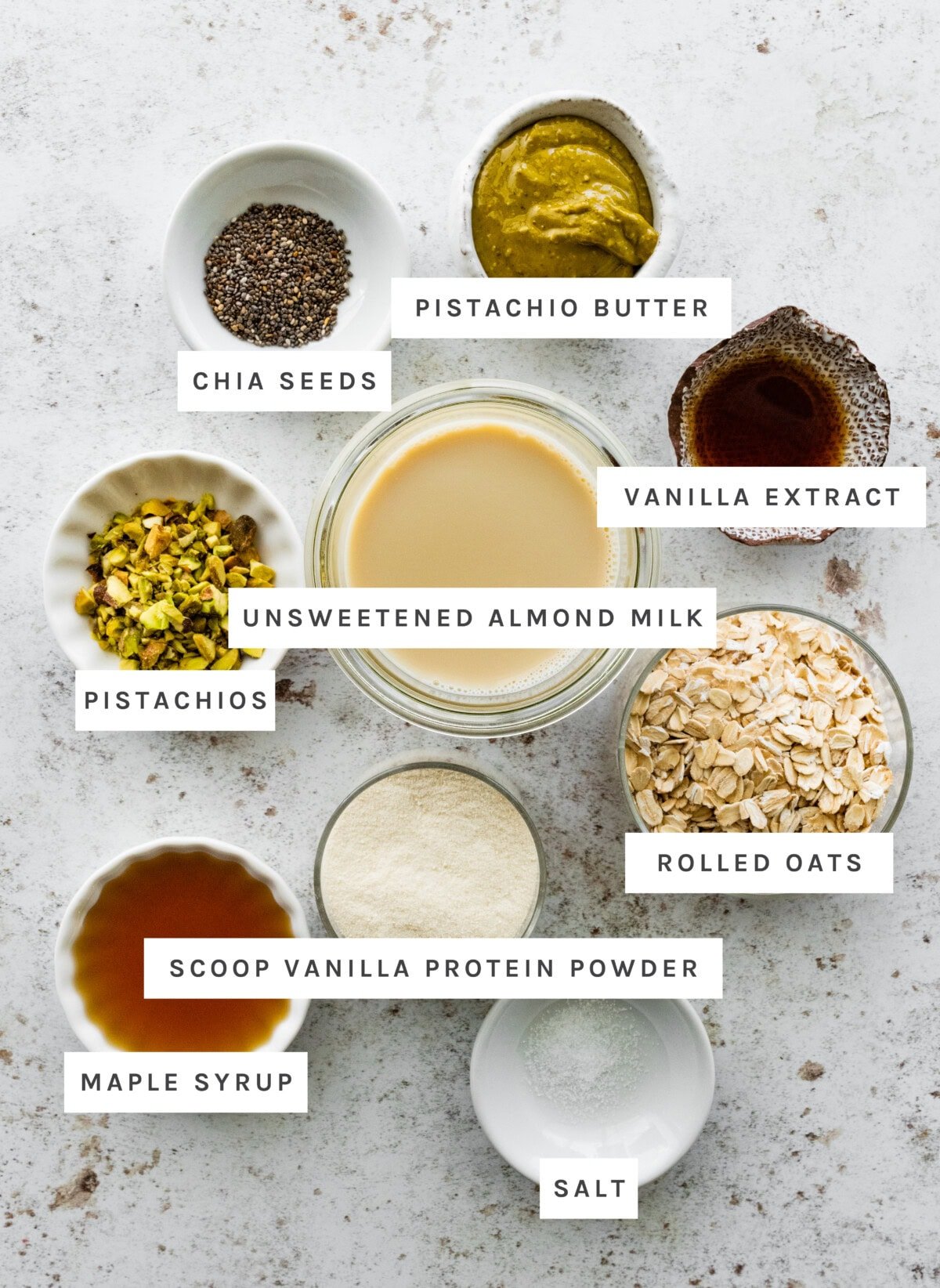 Pistachio Overnight Oats ingredients: Chia seeds, pistachio butter, vanilla extract, unsweetened almond milk, pistachios, rolled oats, scoop vanilla protein powder, maple syrup, salt.