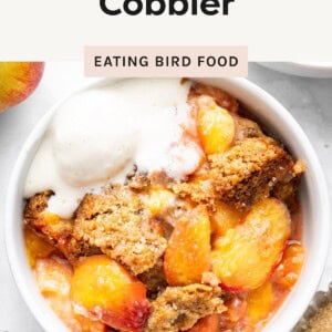 Bowl of healthy peach cobbler topped with a scoop of vanilla ice cream.