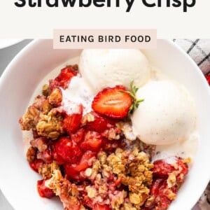 A bowl of high-protein strawberry crisp topped with vanilla ice cream and fresh strawberries, served as a healthy summer dessert.