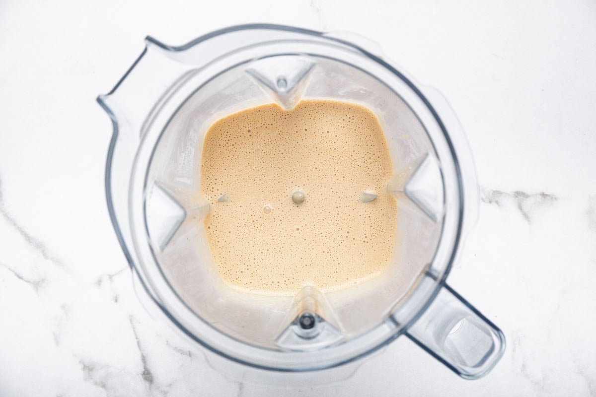 Creamy sesame dressing freshly blended in a high-speed blender, ready to pour over slaw ingredients.