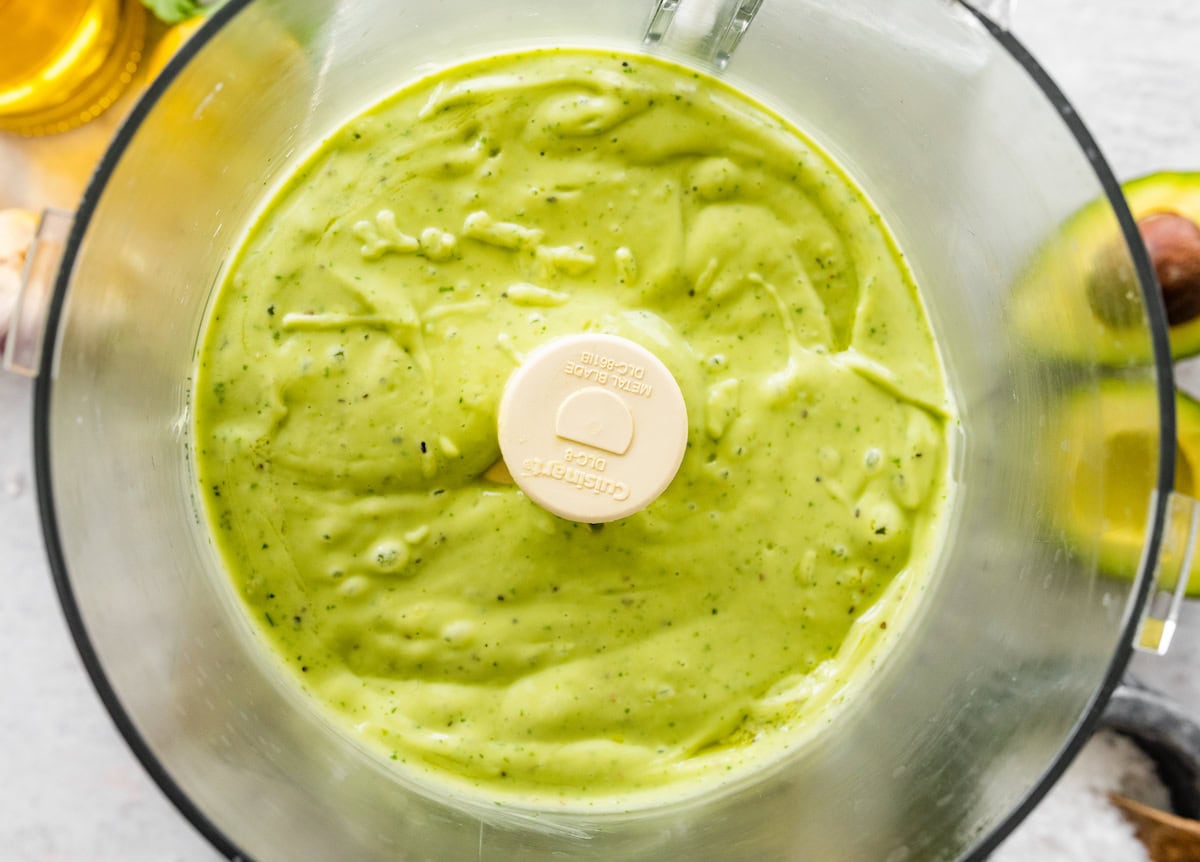Blended avocado dressing in a food processor.