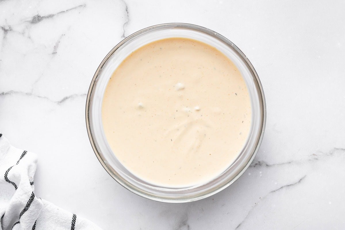 Creamy Big Mac sauce in a glass bowl on a white marble surface.