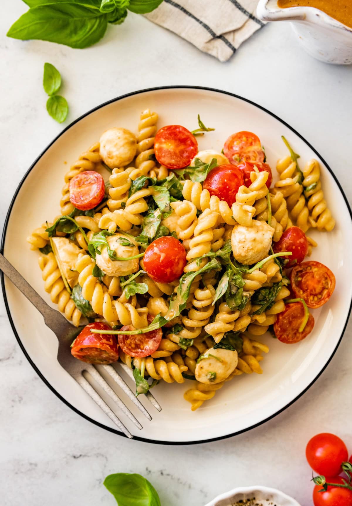 Caprese pasta salad served on a plate with a fork.
