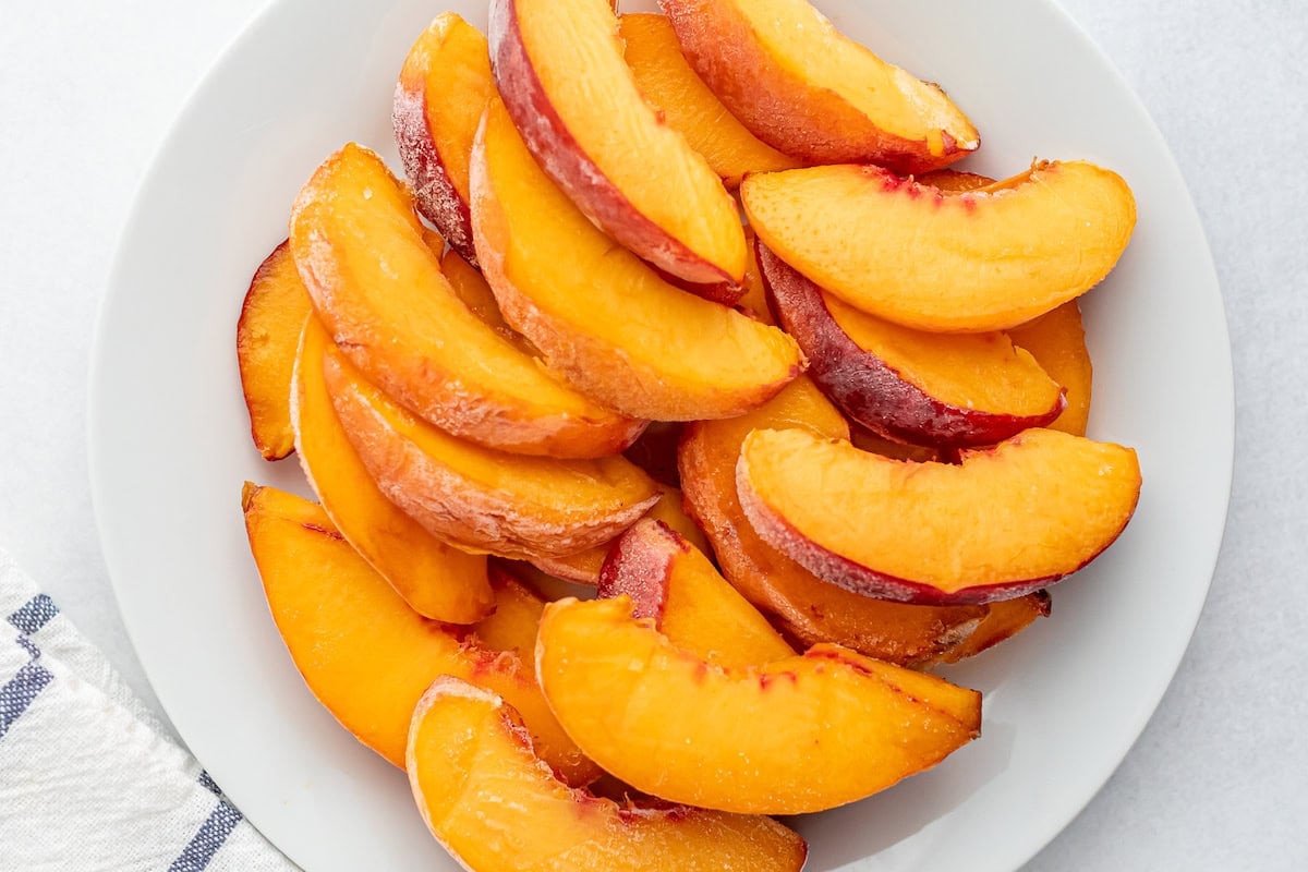 Sliced peaches on a white plate.