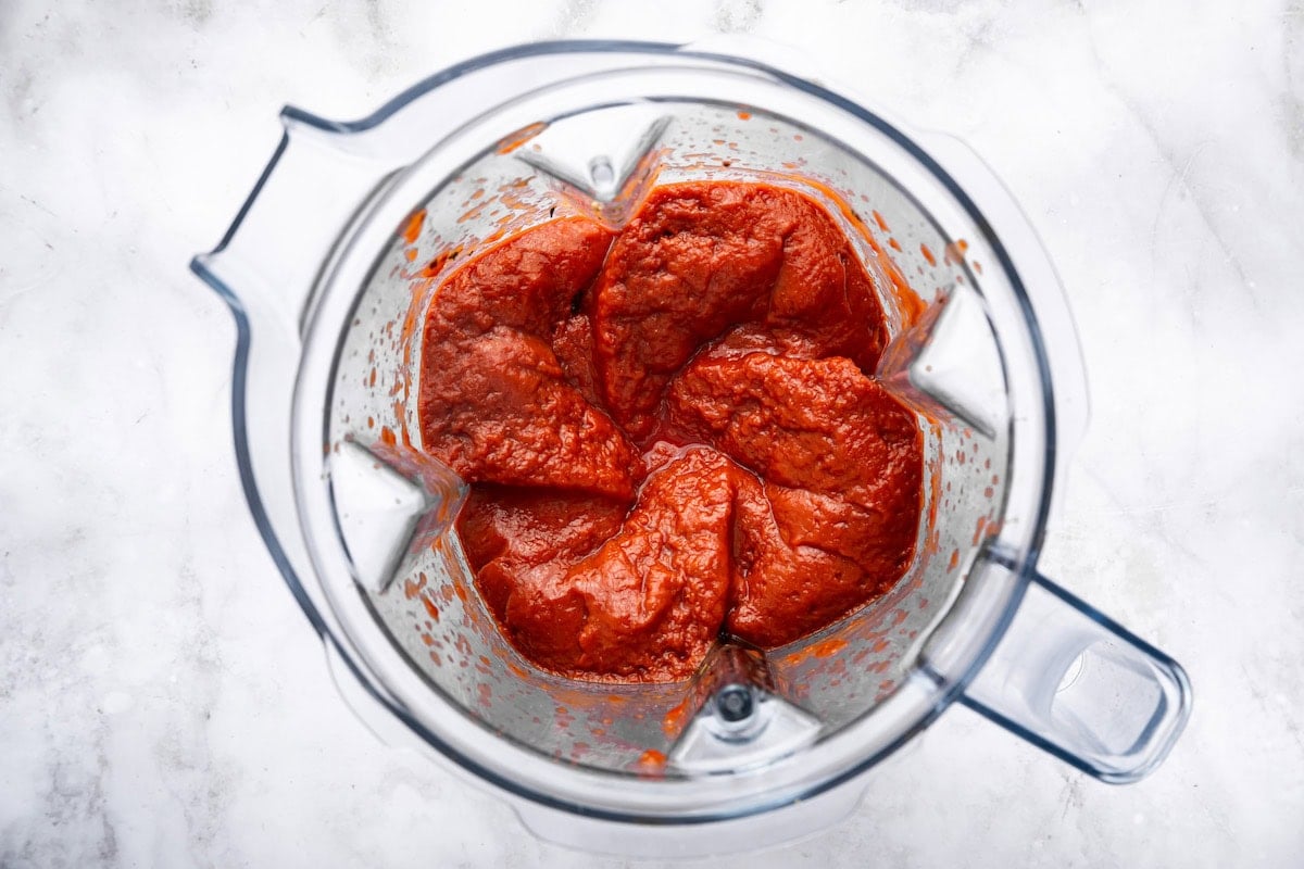 Tomato sauce and herbs blended together in a blender for homemade pizza sauce.