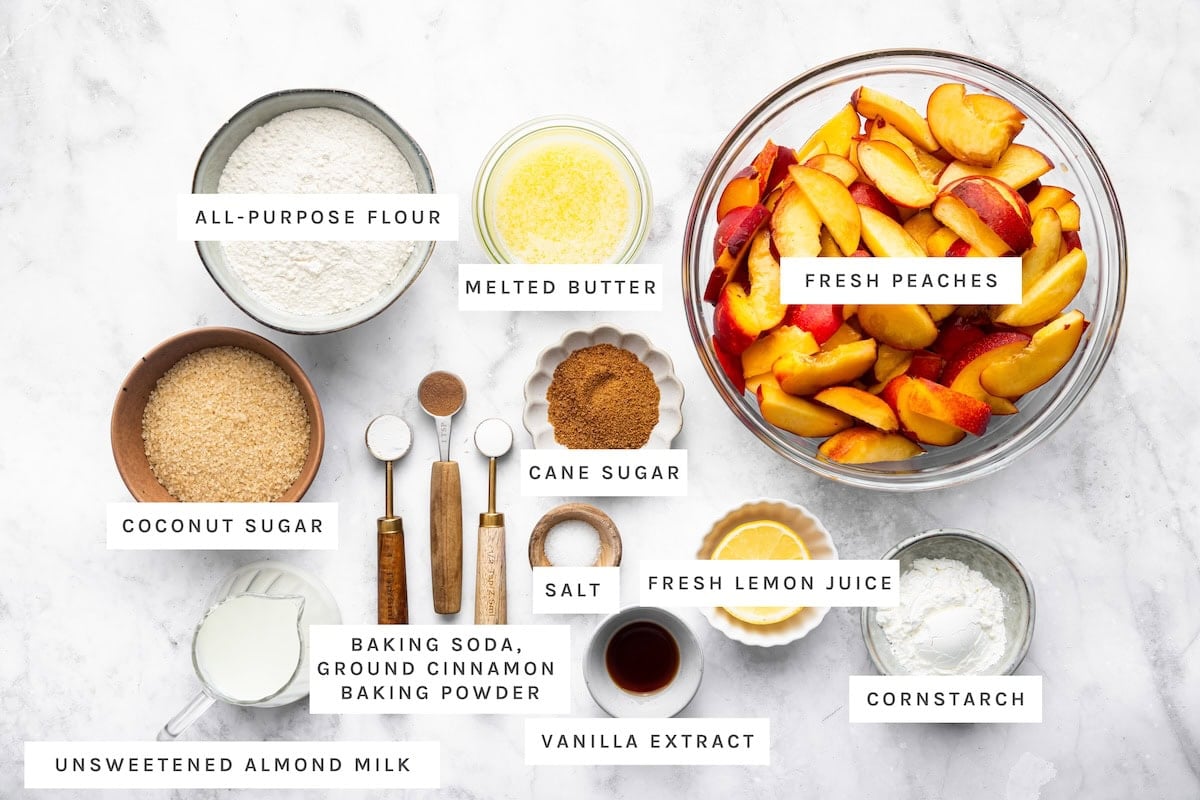 Healthy Peach Cobbler ingredients: All-purpose flour, melted butter, fresh peaches, coconut sugar, cane sugar, salt, fresh lemon juice, cornstarch, unsweetened almond milk, baking soda, ground cinnamon, baking powder, vanilla extract.