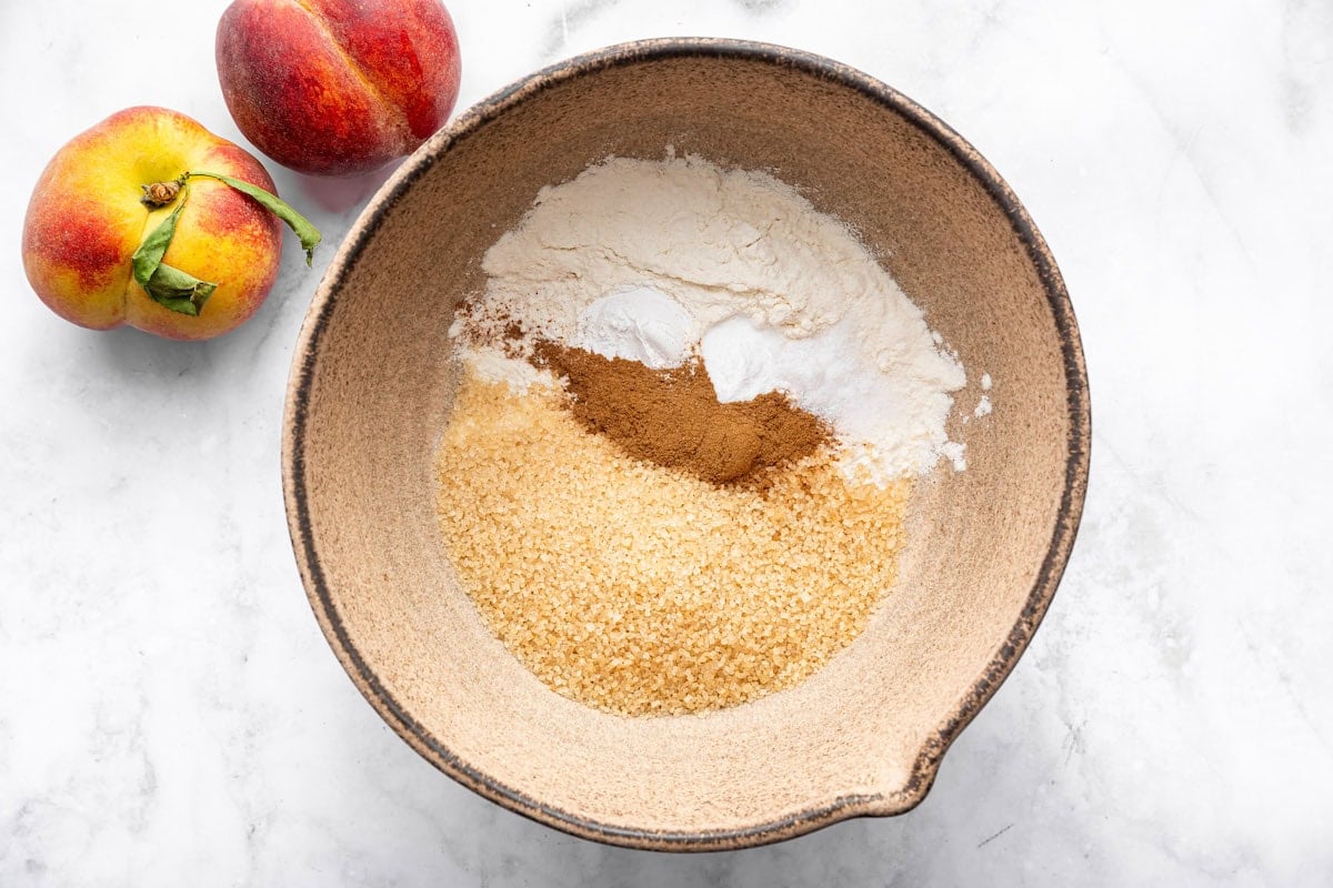 Mixing bowl with flour, coconut sugar, baking soda, and cinnamon before adding wet ingredients for the cobbler topping.