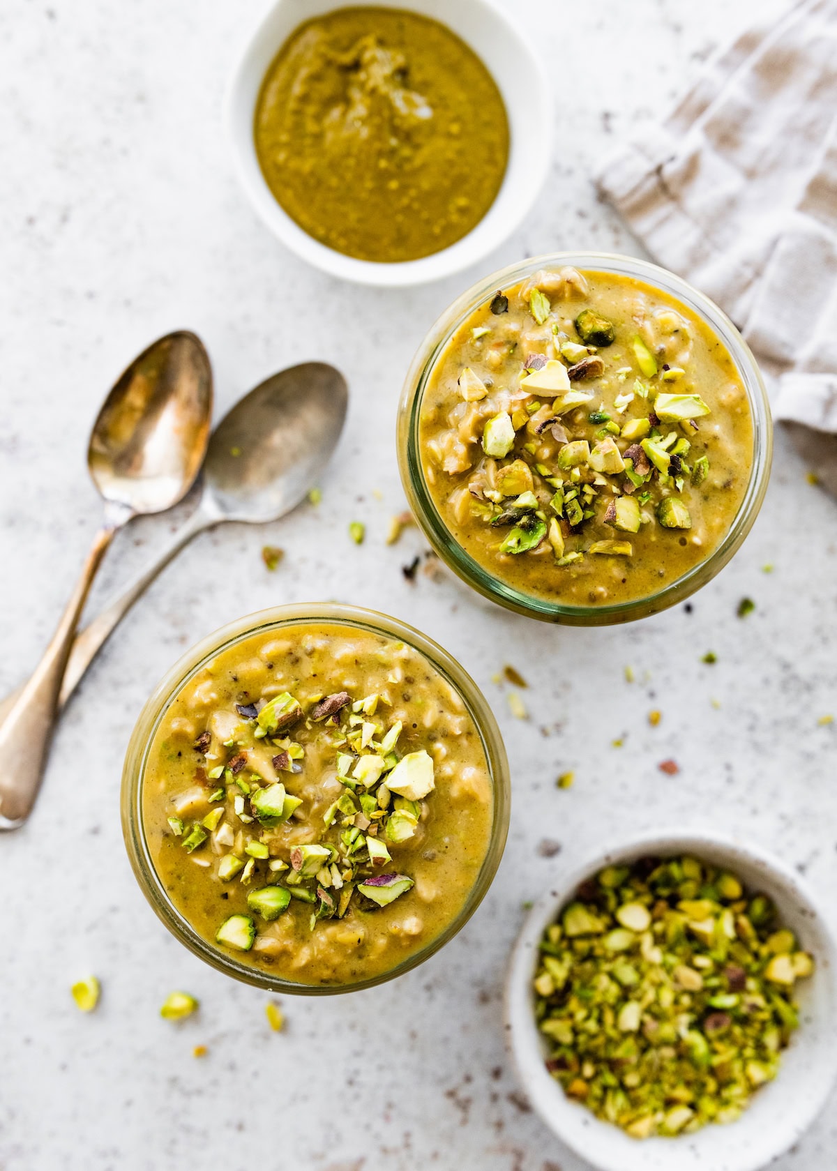 Two jars of pistachio overnight oats topped with chopped pistachios.