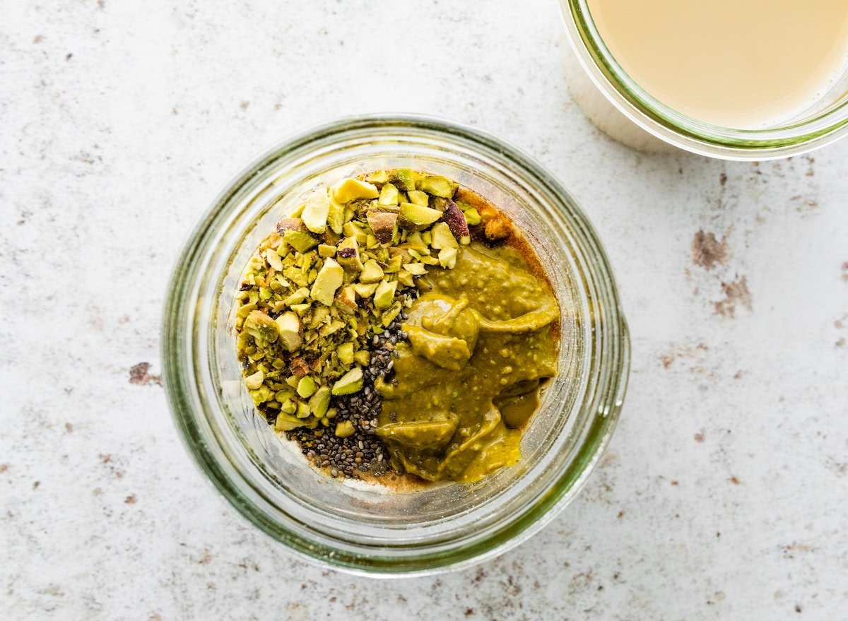 All of the ingredients for the pistachio overnight oats in a glass jar before being mixed up.