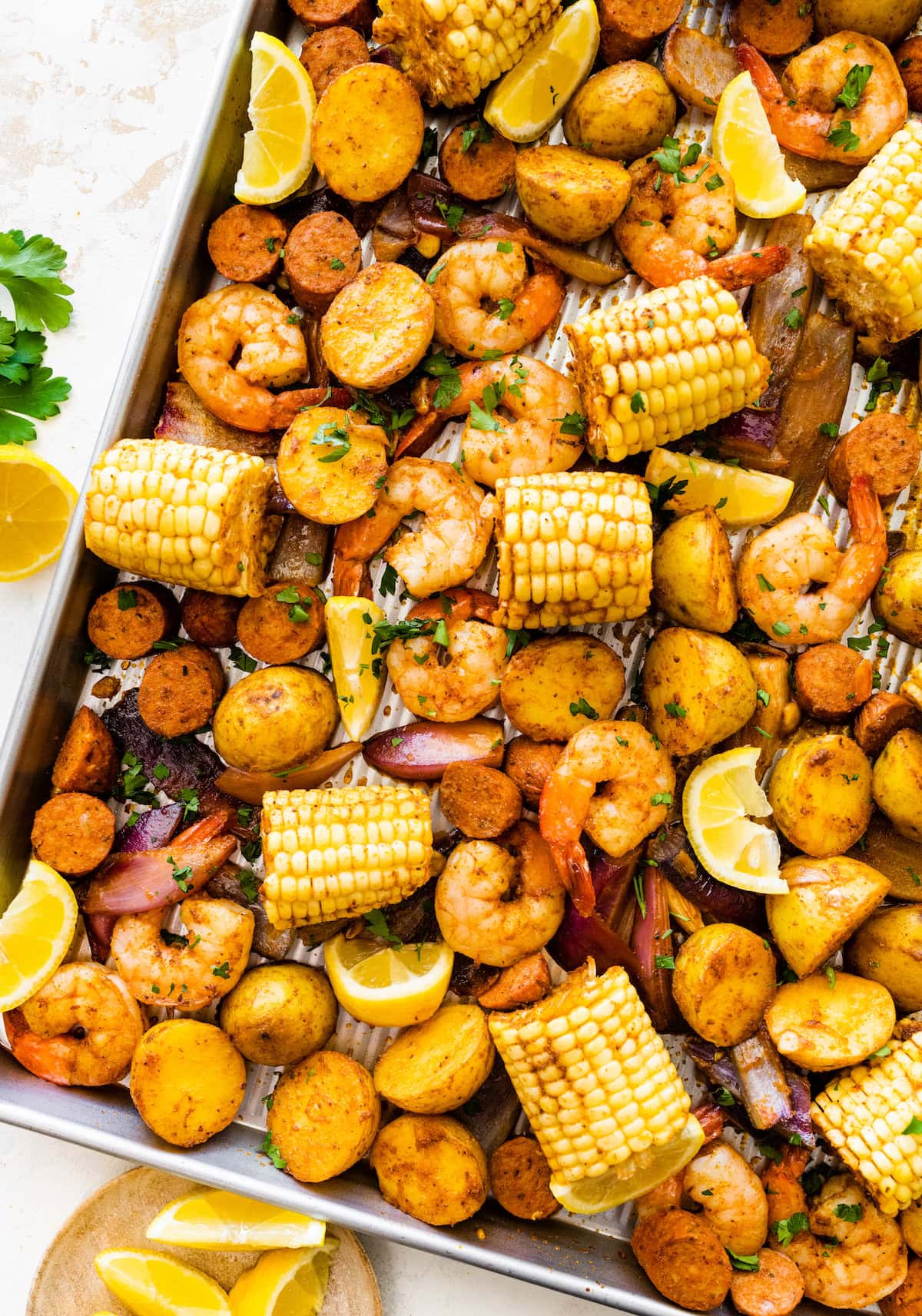 Sheet pan shrimp boil with golden potatoes, shrimp, sausage, and corn.