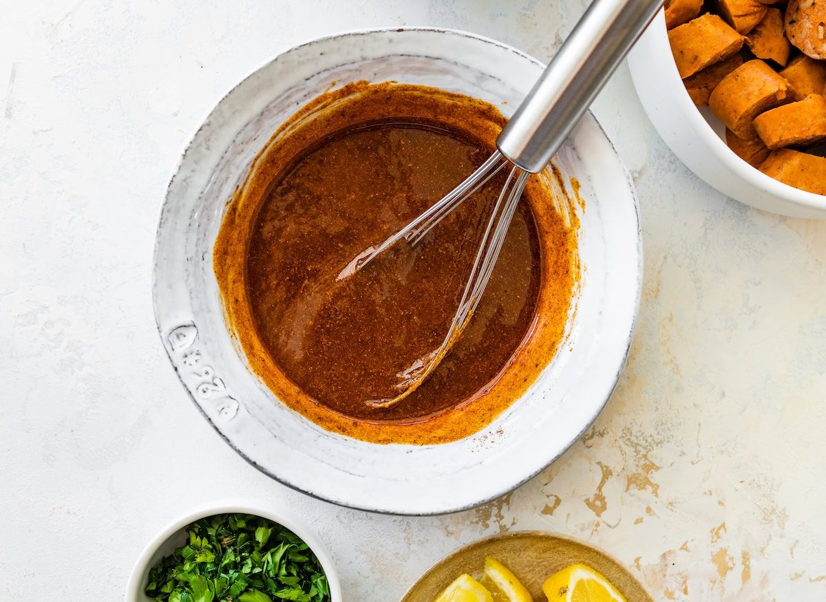 Spiced melted butter mixture being whisked in a white bowl.