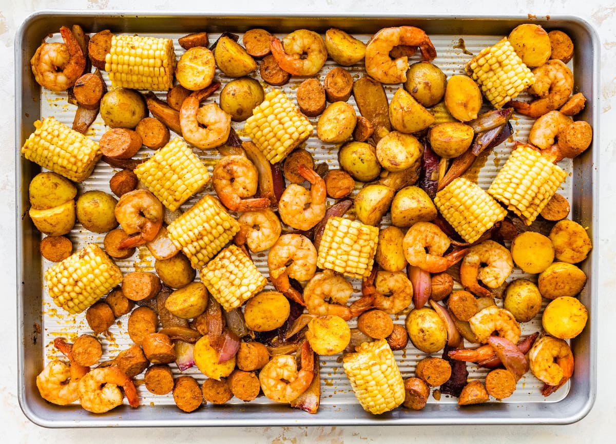 Sheet pan filled with roasted shrimp, sausage, corn, and potatoes straight from the oven.