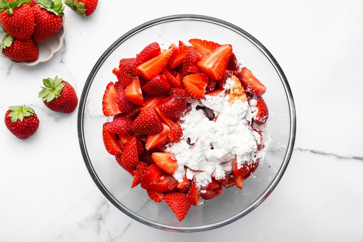 Strawberry slices in a glass bowl topped with arrowroot powder.