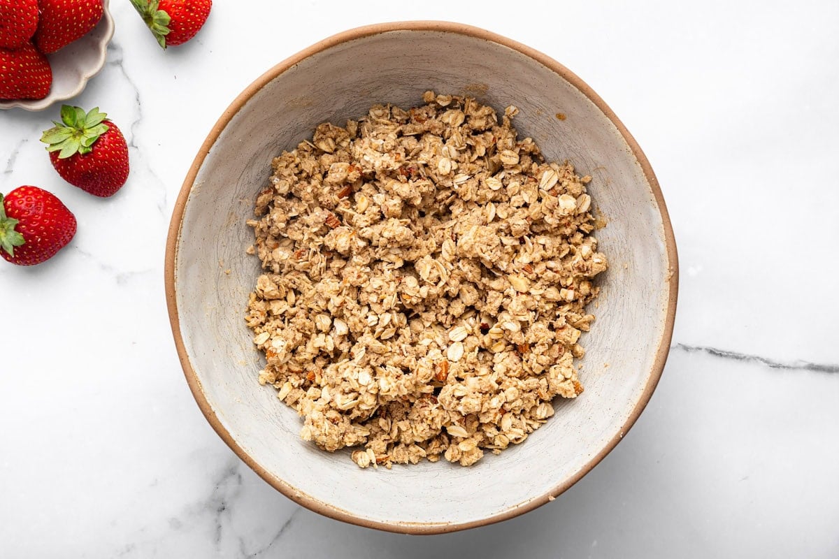 The oat almond crumble topping for the strawberry crisp in a mixing bowl.