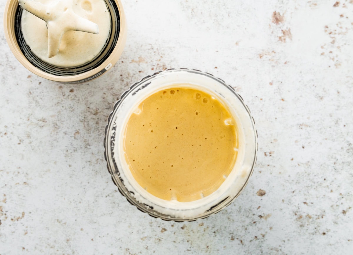 Blended tahini sauce in the base of blender. The blade of the blender is next to the jar.