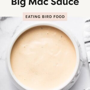 A bowl of creamy light orange sauce labeled “Healthy Big Mac Sauce” by Eating Bird Food, on a white marble surface.