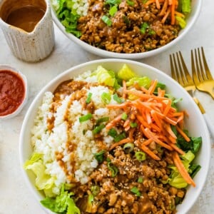 Chicken lettuce wrap bowl with cauliflower rice, shredded carrots, and peanut sauce on the side.
