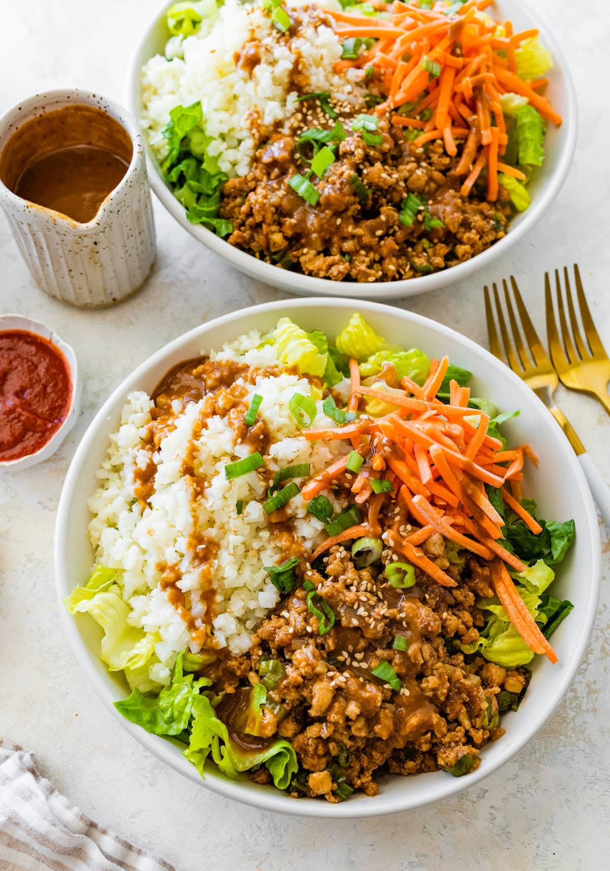 Chicken lettuce wrap bowl with cauliflower rice, shredded carrots, and peanut sauce on the side.
