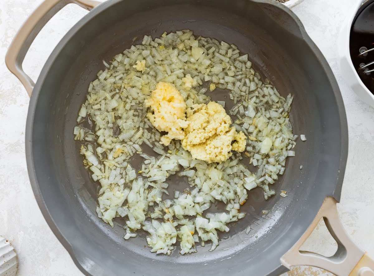 Minced garlic and ginger sautéing in a skillet with oil for chicken lettuce wrap bowls.