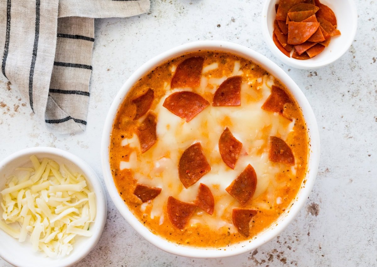 Cottage cheese pizza bowl after microwaving, topped with melted mozzarella cheese and chopped turkey pepperoni.