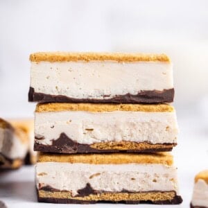 Three frozen s’mores bars stacked on top of each other showing distinct graham cracker, chocolate, and whipped protein layers.