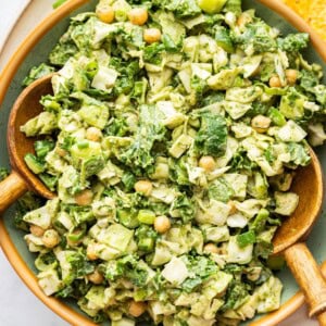 Green goddess salad with wooden salad servers, served with tortilla chips.