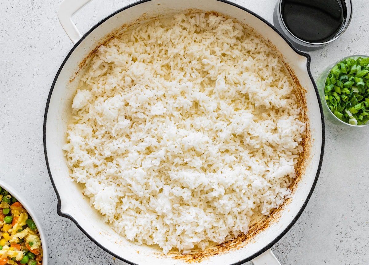 Cold cooked jasmine rice spread in a skillet to crisp and brown for fried rice.