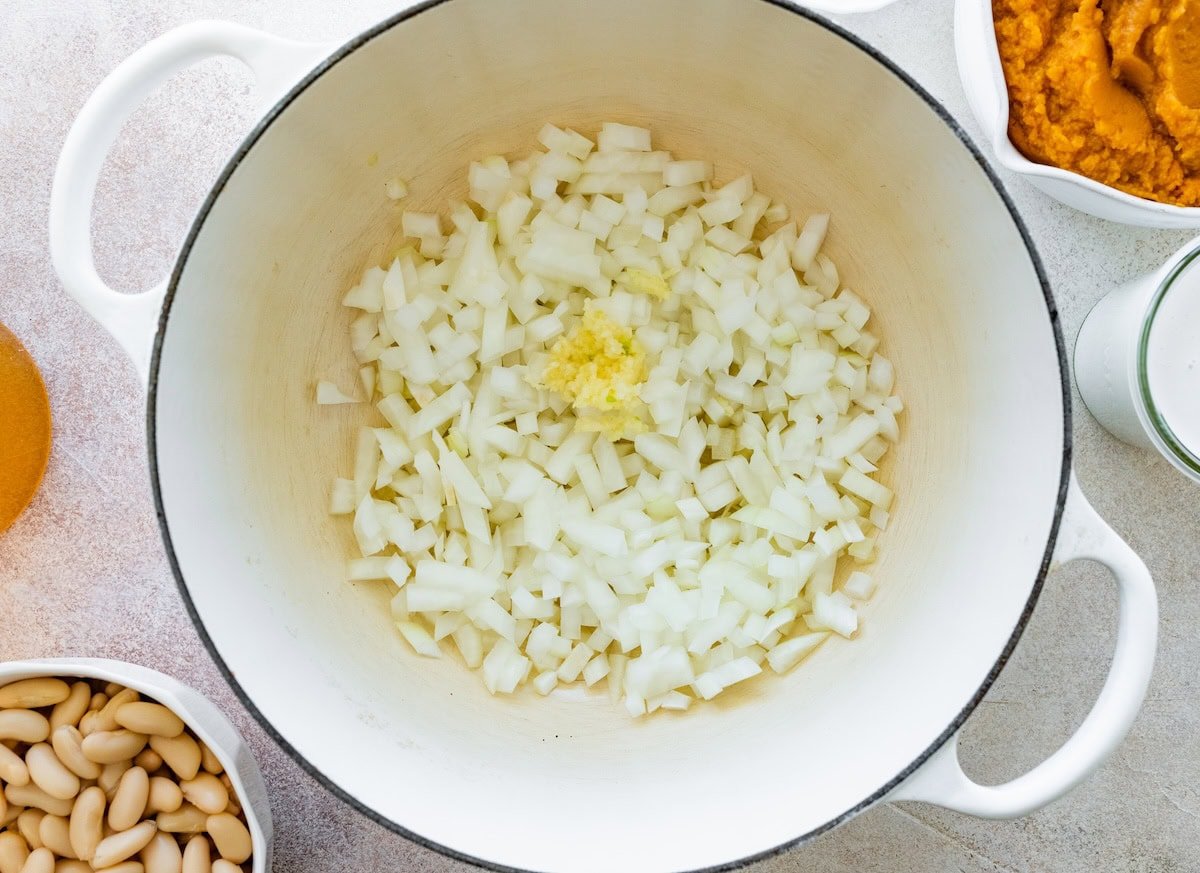 Raw onion and garlic in a large pot ready to be sauteed for a pumpkin curry soup.