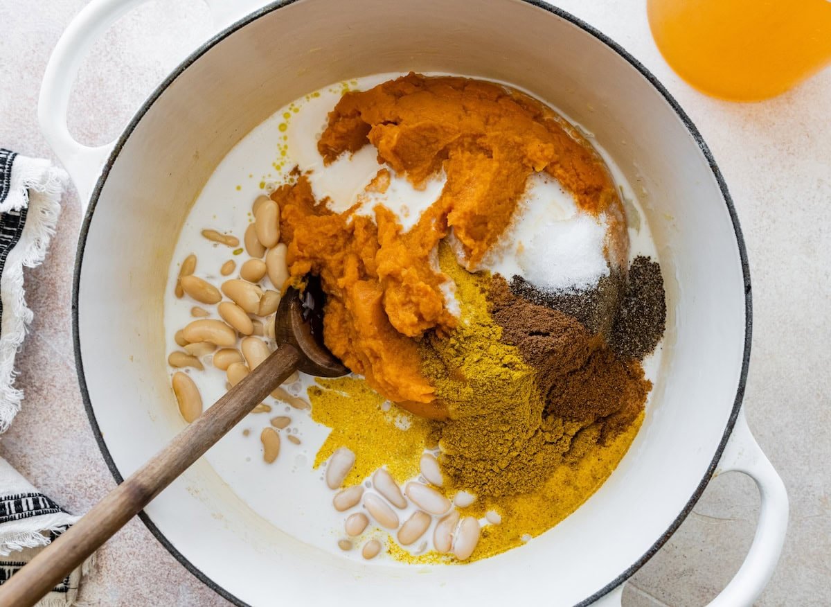 A large pot full of pumpkin puree, beans, coconut milk, onion, garlic, broth, and plenty of spices.