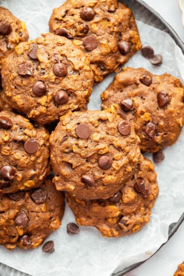 Close-up of chewy pumpkin oatmeal cookies with chocolate chips on parchment paper.