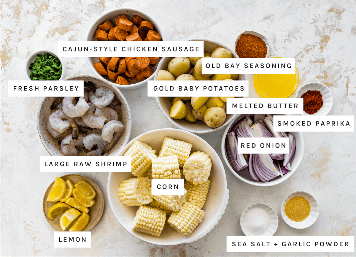 Easy Sheet Pan Shrimp Boil ingredients: Cajun-style chicken sausage, gold baby potatoes, Old Bay seasoning, melted butter, smoked paprika, red onion, sea salt, garlic powder, corn, large raw shrimp, lemon, fresh parsley