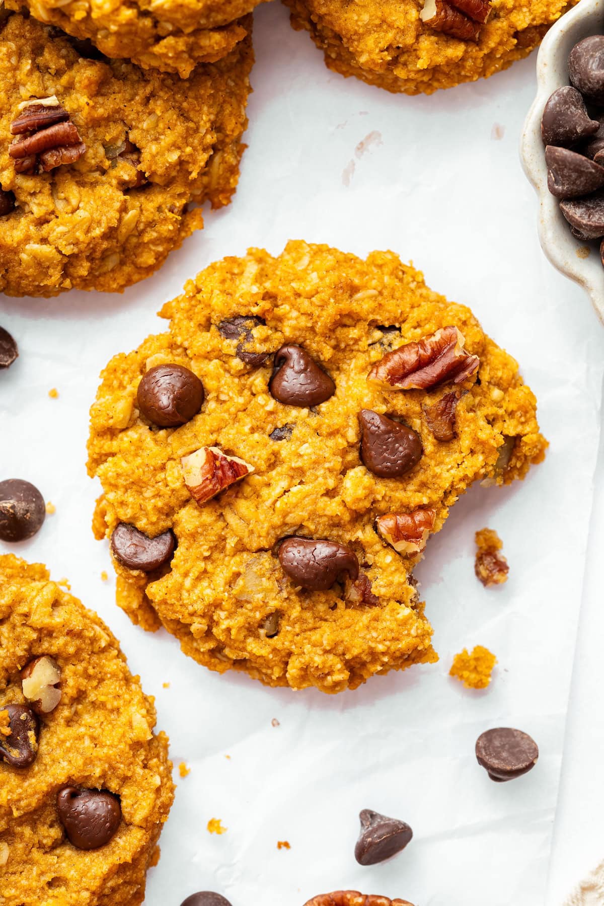 A sweet potato breakfast cookie with chocolate chips, pecans, and a bite taken from it.