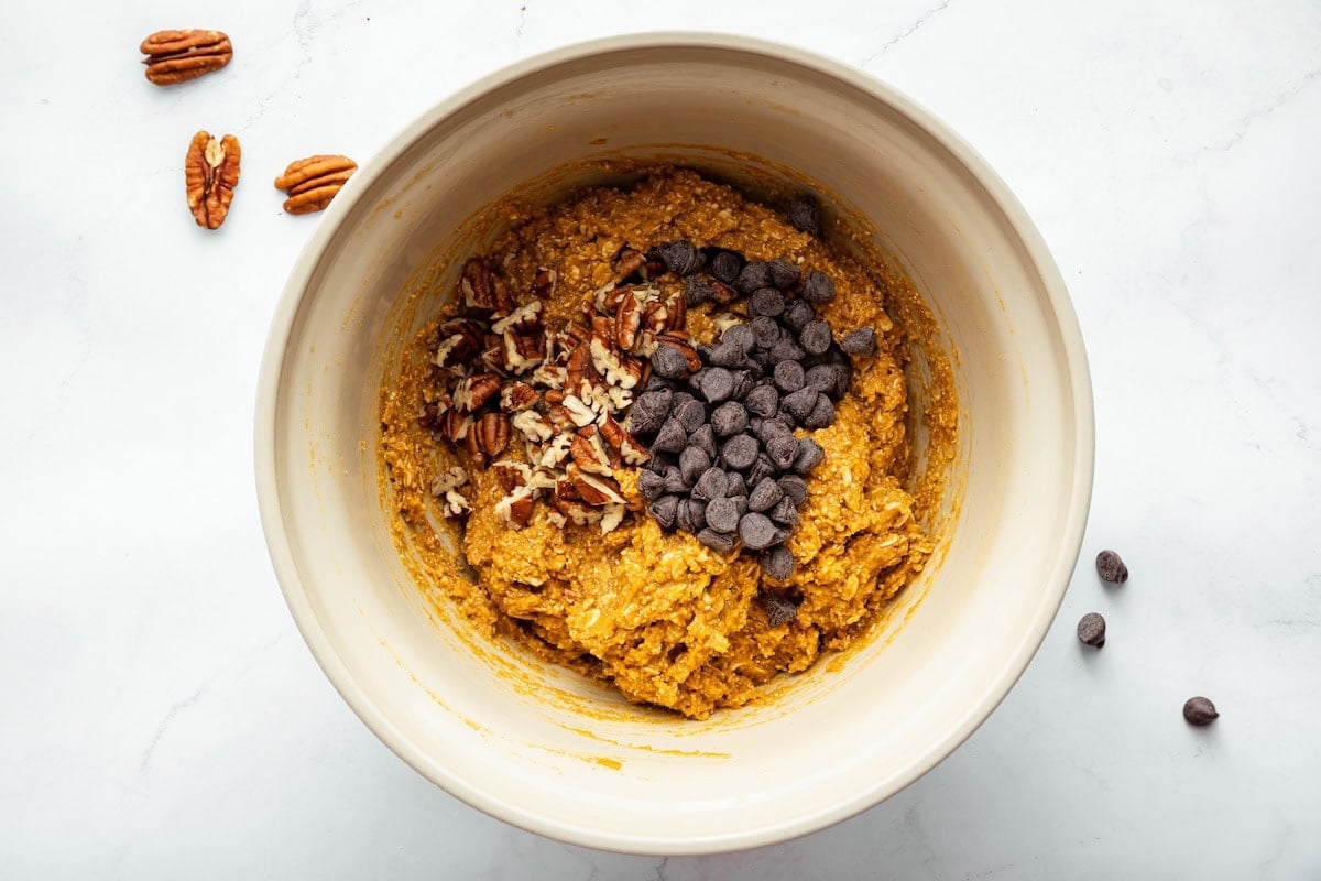 Chocolate chips and pecans added to a bowl of sweet potato breakfast cookie dough.