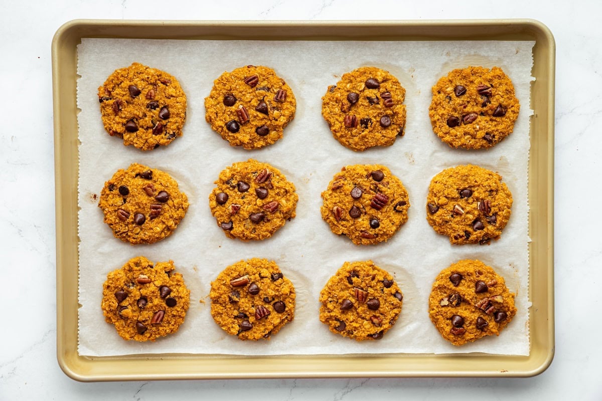 Twelve sweet potato breakfast cookies on a baking sheet after being baked.