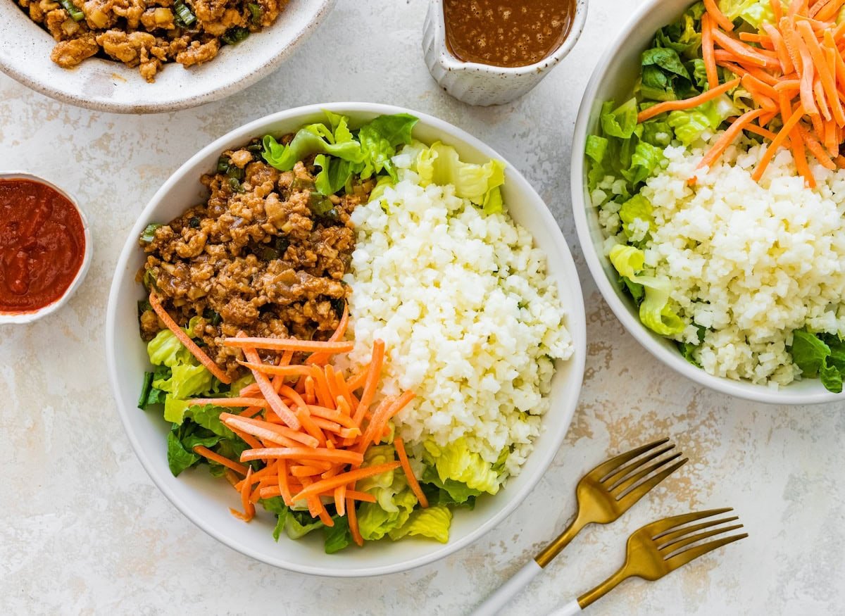 Lettuce wrap bowl with ground chicken, cauliflower rice, and shredded carrots before adding sauce.