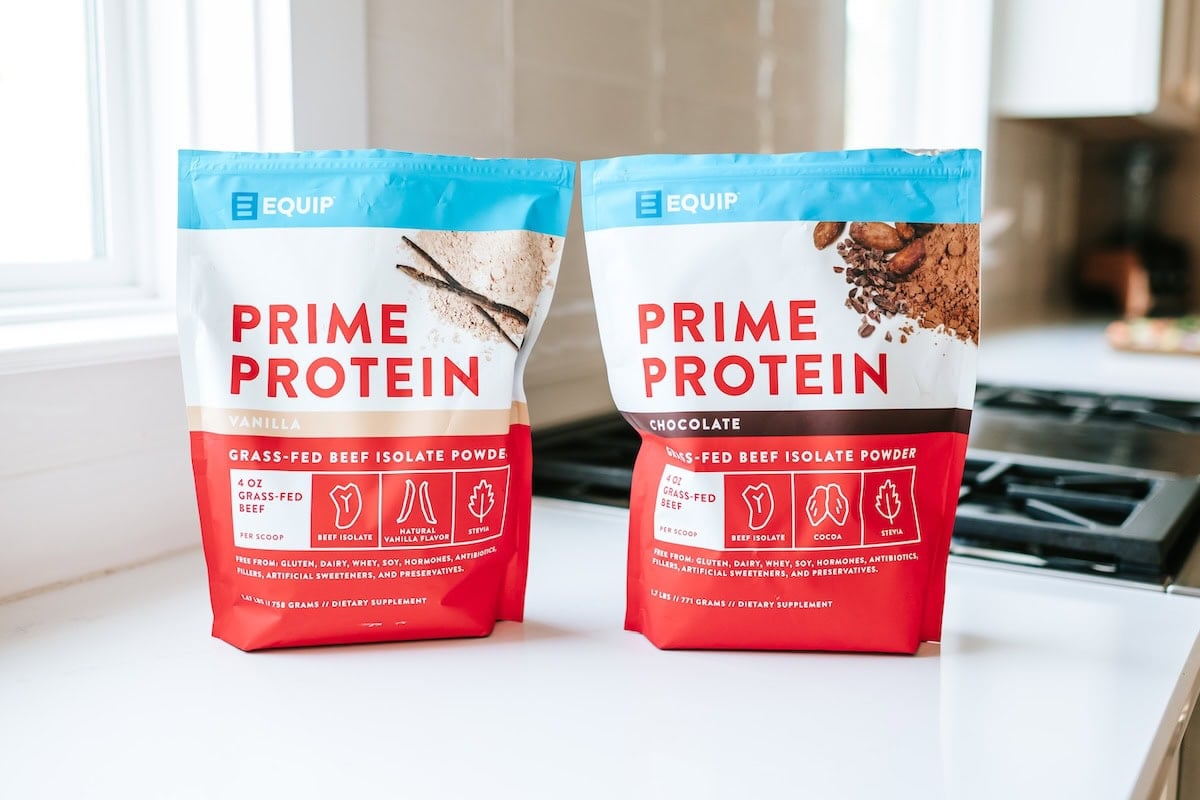 Two pouches of Equip Prime Protein powder, one vanilla and one chocolate flavor, displayed on a kitchen counter.