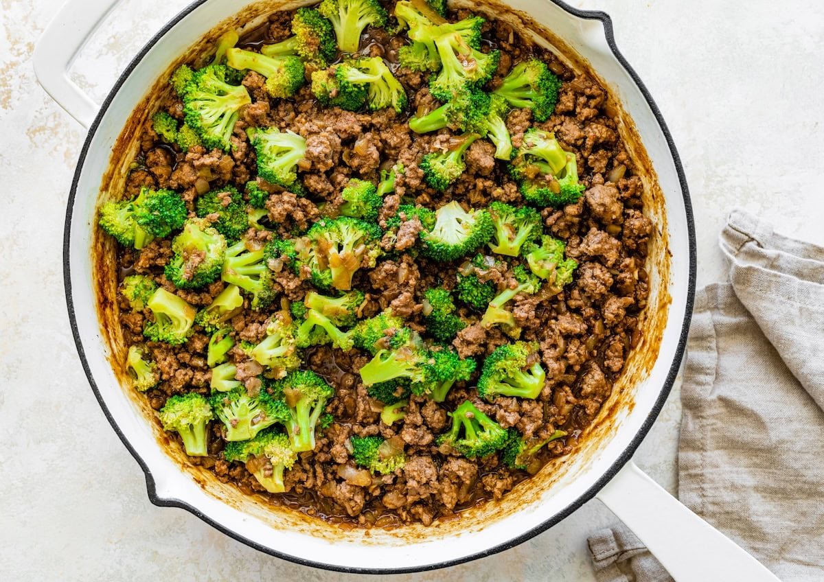 A white skillet filled with ground beef and broccoli.