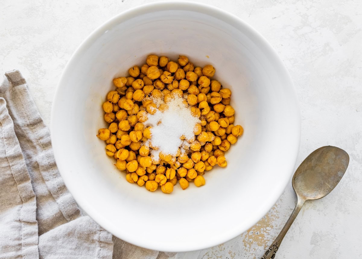 Chickpeas tossed with oil and seasonings in a white mixing bowl.