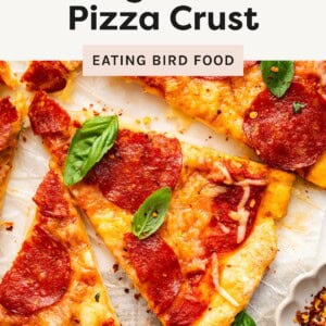 Close-up of sliced pepperoni pizza with melted cheese and fresh basil leaves on a cottage cheese crust.