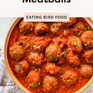 Pan of baked meatballs in marinara sauce, topped with fresh herbs.