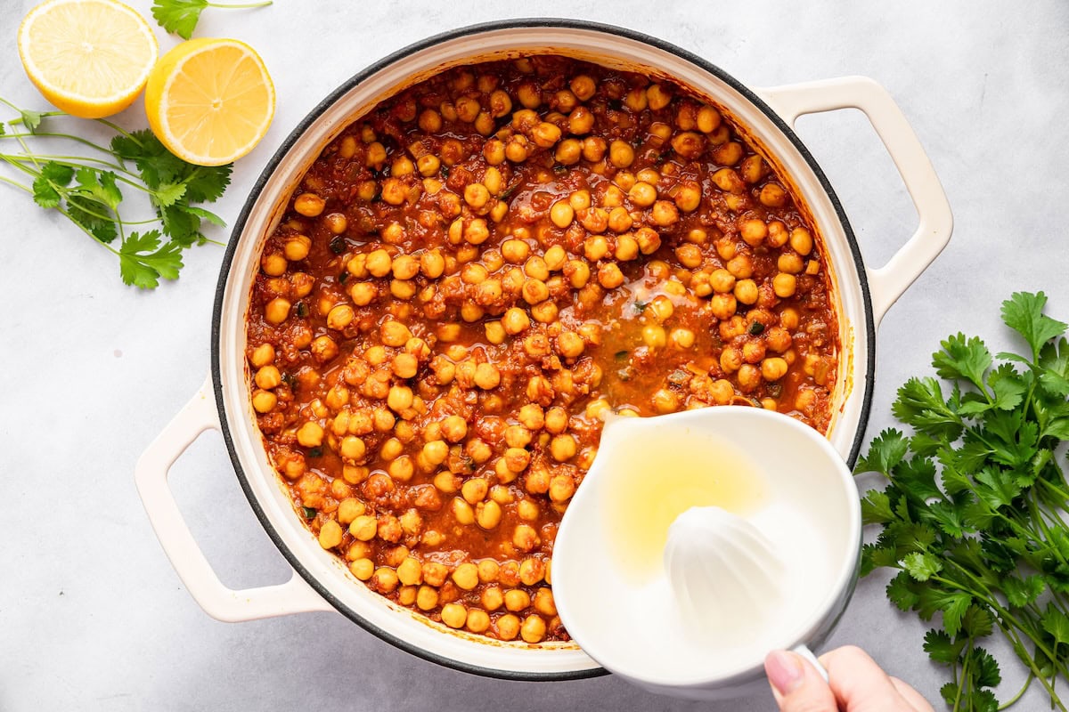Fresh lemon juice being added to chana masala for brightness and flavor.